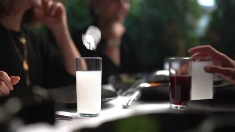 People are chatting while ice is poured into the raki glass at the raki table Stock Footage 180499016