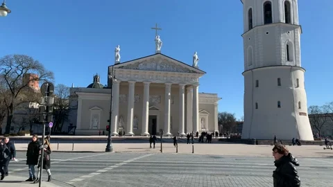 People are crossing intersection in front of Vilnius Cathedral and Bell tower Stock Footage 222578409