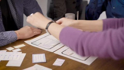 People are developing interface of mobile apps, putting papers on table in Stock Footage 120407066