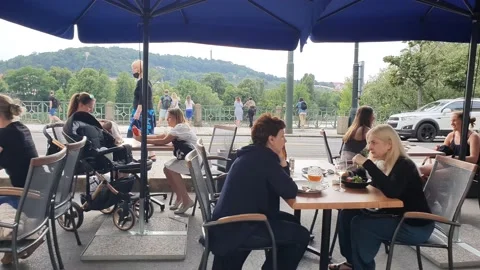 People are resting in a restaurant. Tables on the street by the road. Stock Footage 166403903