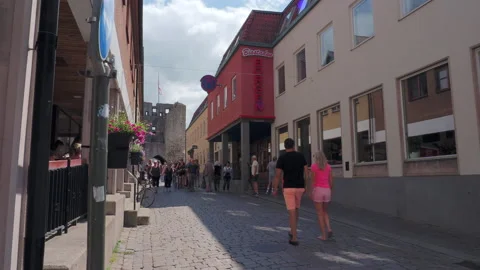 People are strolling on paved stones beside the cinema in the old town Visby Stock Footage