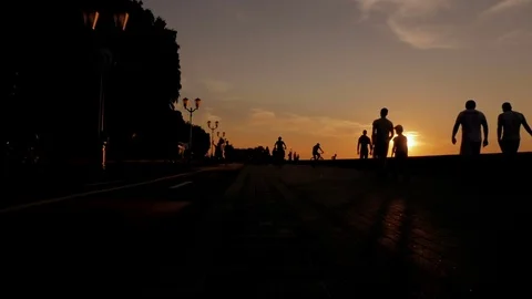 People are walking on the beach during sunset. Silhouettes of men, women and Vídeos de archivo 77998328