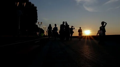 People are walking on the beach during sunset. Silhouettes of men, women and 库存影片 78001503