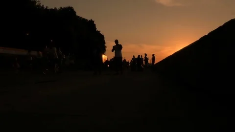 People are walking on the beach during sunset. Silhouettes of men, women and Video stock 78124143