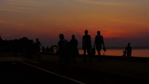 People are walking on the beach during a beautiful sunset. Silhouettes of men 库存影片 87866261