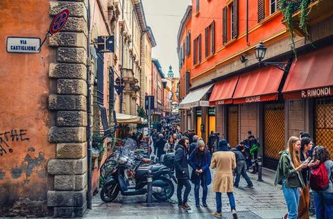 People are walking down typical italian street with buildings with bright col Stock Photos
