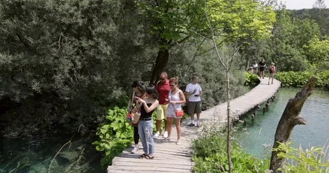 People at bat bridge admiring a waterfall at the Plitvice lakes, Croatia Stock Footage 79577974