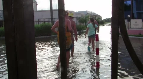 People in bathing suits go through water on the street Stock Footage 64259949