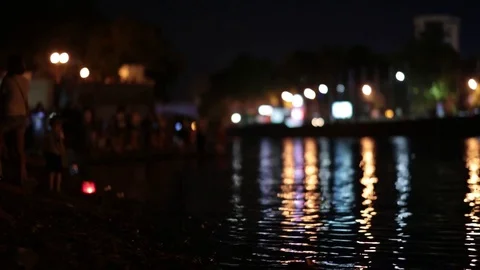 People on the beach at night. Lights reflections on the water. Video stock 77233894