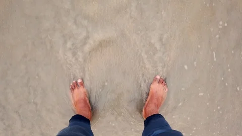 People at a beach. A normal speed of waves come crushing at a feet. Видео 118227336