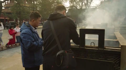 People Burning Incense and Praying at Outdoor Altar in Lama Temple Courtyard Stock Footage 345828786