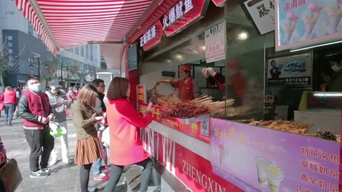 People buying fried squids at a local stall in Jinma Biji Square, Kunming Stock Footage 71571568