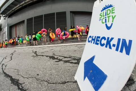 People Carrying Innertubes Wait In Long Line At Waterslide Event Stock Photos