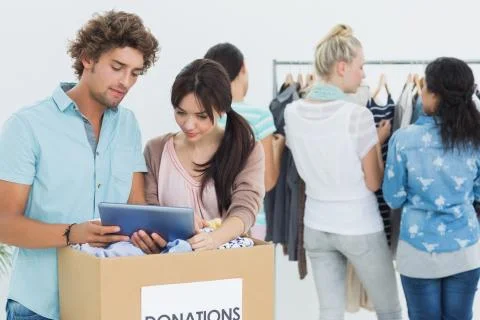 People with clothes donation while using digital tablet Foto stock