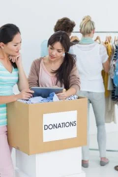 People with clothes donation while using digital tablet Foto stock