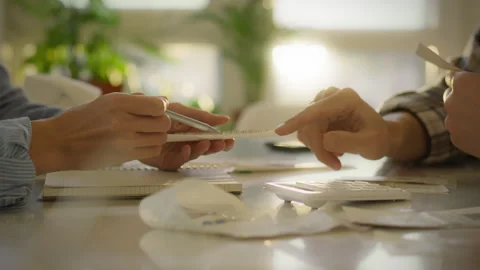 People collaborating on financial planning at a bright table during a sunny Stock Footage 323868284