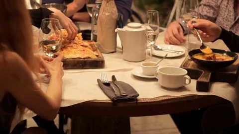 People communicate over evening dinner at a restaurant table under muffled light Stock Footage