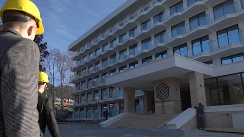 People in construction helmets go on a construction site. Businessmen inspect Stock Footage 125035212