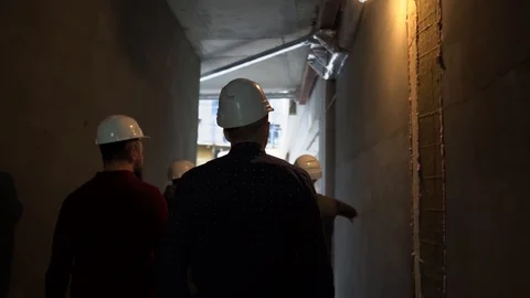 People in construction helmets go on a construction site. Businessmen inspect Stock Footage 125035411