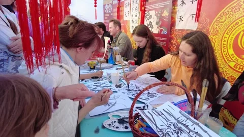 People create art with brushes during a local festival in an outdoor setting Stock Footage 340357268
