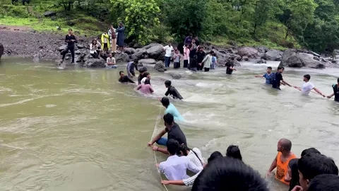 People Crossing High Flow River With Rope During Monsoon 4K Stock Footage 346429791