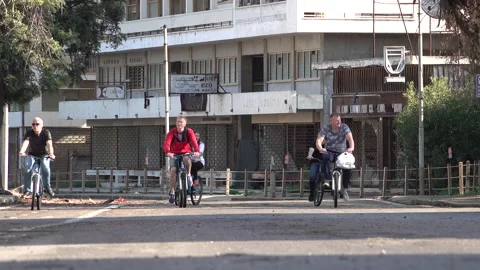 People cycle through reopened ghost town Varosha, politics conflict Cyprus Stock Footage 237687096