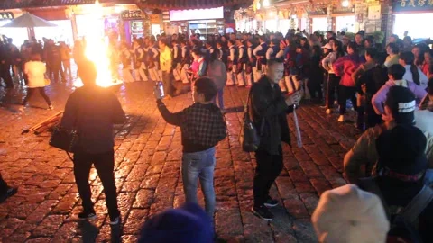 People dance around a fire in the old town of Lijiang, Yunnan province, China Stock Footage 336749989