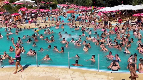 People dance in the swimming pool to rhythmic music. A crowd of people is having Stock Footage 250354420