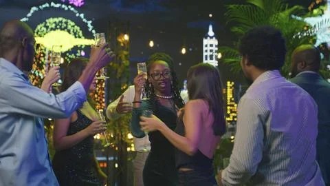 People dancing and having fun during New Year Eve on colorful rooftop terrace Stock Photos