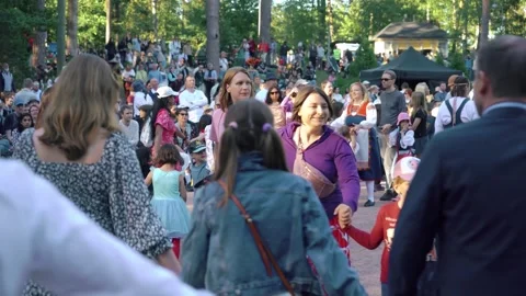 People dancing in a circle during a traditional Finnish midsummer celebration Stock Footage 309920779