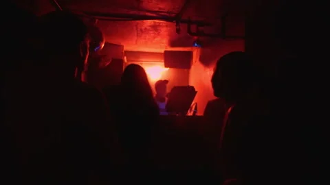 People dancing to a dj set in a dark nightclub Видео 335042934