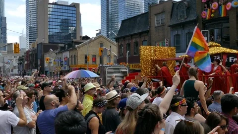 People dancing on glittered up float in gay parade in front of crowd - 24fps Stock Footage 104118896
