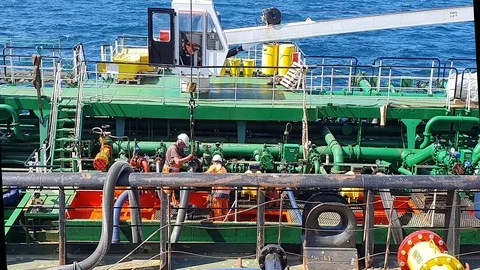 People on decks work with black hosepipe between oil tankers Stock Footage 113194470