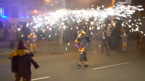 People in devil costumes dance at night on the street with lots of lights Video stock 125642871
