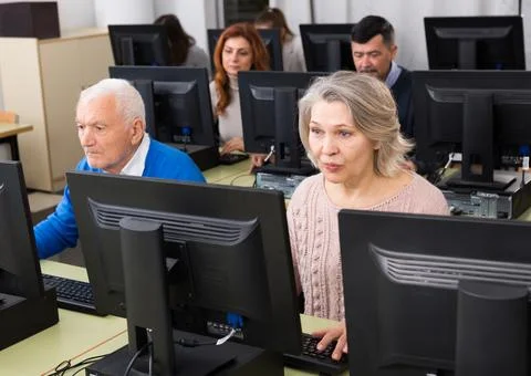 People of different age studying in computer class Stock Photos
