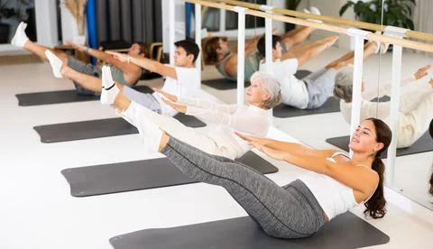 People different ages performing set of pilates exercises in fitness studio Stock Photos
