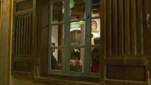 People dining inside a warmly lit restaurant viewed through an old wooden 스톡 동영상 344718815