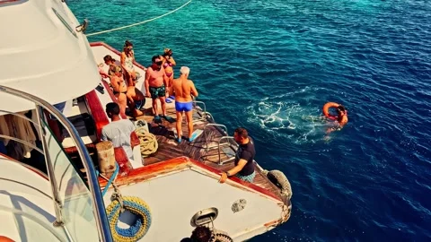 People diving from yacht deck into Red Sea waters during sunny day boat Stock Footage 332609073