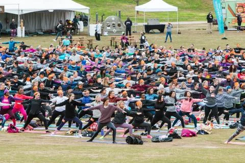 People Do Warrior II Pose In Massive Outdoor Yoga Class Foto stock