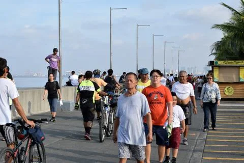 People doing walking exercise along ocean bay break water Fotos de archivo