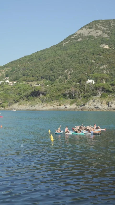 People doing yoga on SUP paddleboard, vertical shot, Elba, Italy. June 1, 2026. Stock Footage 336315291