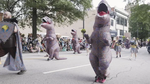 People dressed in T Rex dinosaur costumes walk in parade Stock Footage 296138210