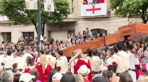 People dressed in white with spears carry large wooden cross Stock Footage 47969578