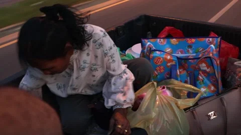 People drive on a loaded back of a pickup through the evening city Video stock 307978769