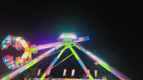 People enjoying a colorful thrill ride spinning at a funfair amusement park at Vídeo Stock 344021453
