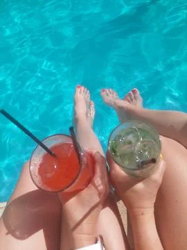 People Enjoying Refreshing Drinks by the Edge of a Blue Swimming Pool Stock Photos
