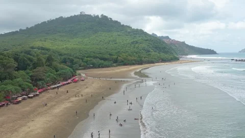 People enjoying a tropical beach in java on a cloudy day Stock Footage 328920703