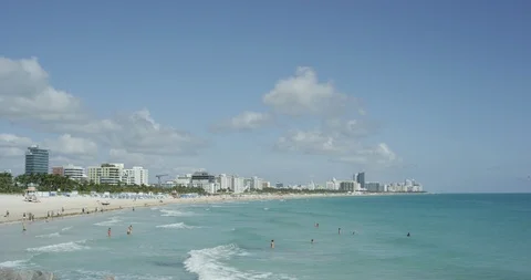 People enjoying the waves rolling in at low tide in South Beach Miami Stock Footage 107634879