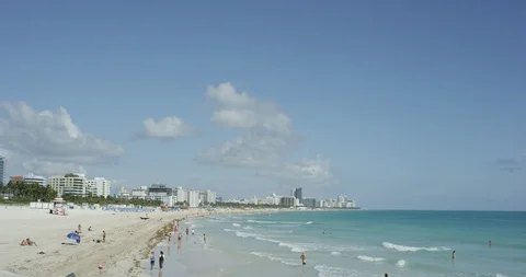 People enjoying the waves rolling in at low tide in South Beach Miami Stock Footage 107635788