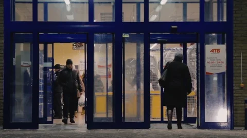 People enter and exit through automatic entrance doors ATB store Stock Footage 101733598
